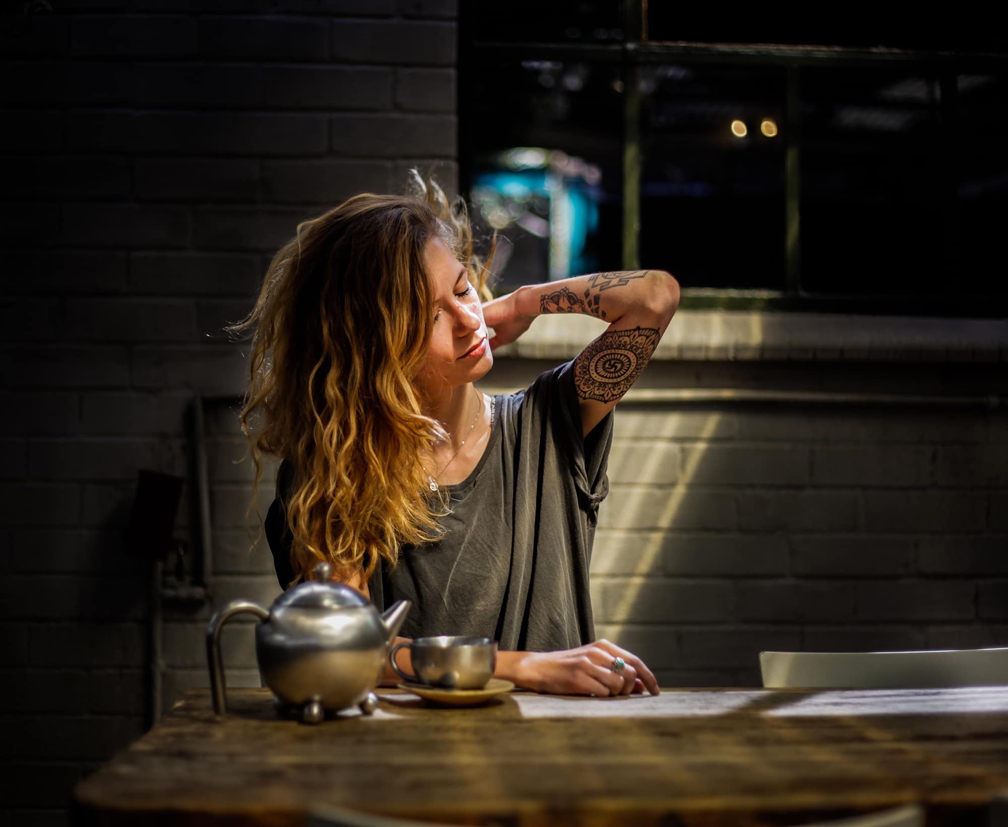 woman sitting at a table with a teapot who is stressed and needs therapy in scottsdale.